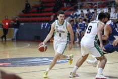 Basketbol maçında oyuncu, top kullanarak hücum ediyor, takım ve seyirci önünde hareketli anlar.