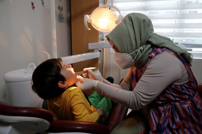 ALT: Çocuk diş muayenesi yapan diş hekimi, rahatlatıcı ortamda tedavi uyguluyor.